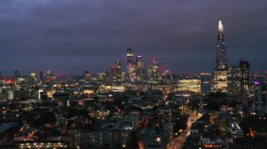 Geceleri gökdelenlerin aydınlatıldığı panoramik hava manzarası. Modern yüksek katlı apartmanın tersten görünümü. Londra, İngiltere