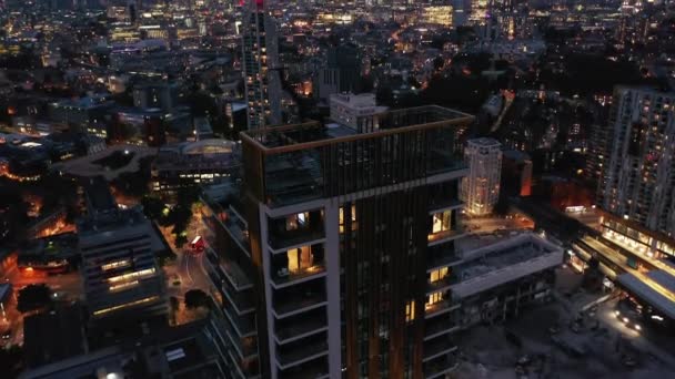 Imágenes descendentes de los pisos superiores del edificio de apartamentos One The Elephant. Inclinado revelando el panorama nocturno de la ciudad. Londres, Reino Unido — Vídeos de Stock