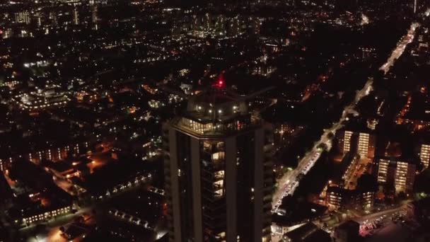 Zdjęcie lotnicze nocnego pejzażu miasta. Przód leci i przechyla się na szczyt wieżowca. Ruch uliczny. Londyn, Wielka Brytania — Wideo stockowe