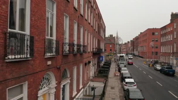 Slider från tegel hus vägg till centrum av smal gata med kyrkan i slutet. Bilar parkerade längs vägen. Dublin, Irland — Stockvideo