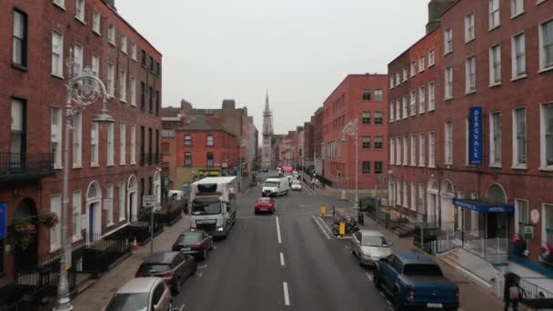 Mobil mengemudi melalui jalan-jalan dan persimpangan jalan. Maju terbang antara rumah bata merah di sisi. Dublin, Irlandia — Stok Video