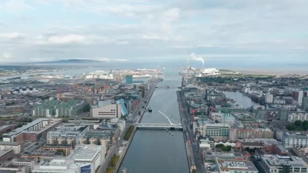 Aerial panoramic footage of town and Liffey river estuary to sea. Modern design Samuel Beckett Bridge. Dublin, Ireland — Stock Video