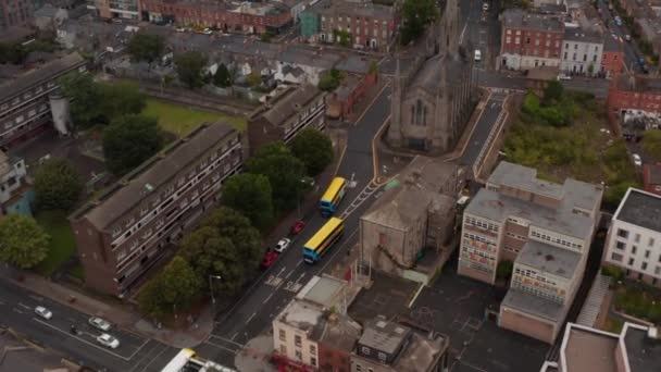 Vista de ángulo alto del grupo de autobuses de colores que conducen a través de la ciudad. Tráfico alrededor de la iglesia histórica. Dublín, Irlanda — Vídeo de stock
