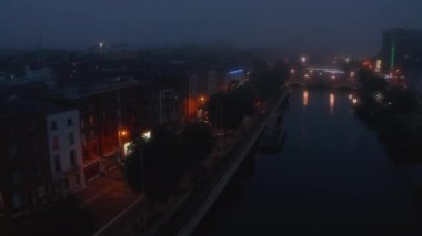 Sisli bir akşamda Liffey nehrinin üzerinde ilerliyorlar. Mütevazı bir şekilde aydınlatılmış deniz manzarası. Dublin, İrlanda