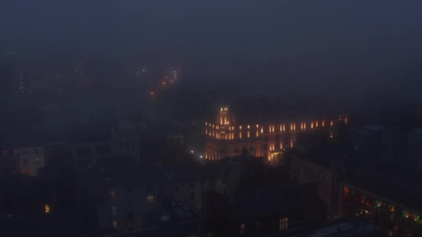 Akşam, sisli havada şehrin üzerinde uçuyor. Varlıklı bir otelin aydınlatılmış güzel binası. Dublin, İrlanda — Stok video