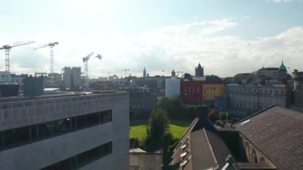 Aumento de tiro de desarrollo de la ciudad y el grupo de grúas torre en el sitio de construcción en segundo plano. Revelando agradable ronda verde Dubh Linn Garden. Dublín, Irlanda — Vídeo de stock