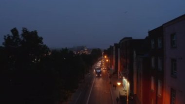 İleri, Liffey nehir setinde giden araçlara karşı uçuyor. Aydınlatılmış rıhtımın akşam görüntüleri. Dublin, İrlanda