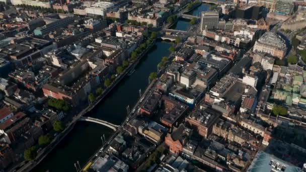 Vista aérea de los distritos de la ciudad a lo largo del río Liffey bajo el sol de la tarde. Inclinado hacia arriba revelan de paisaje urbano. Dublín, Irlanda — Vídeos de Stock