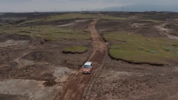 Vista aérea de seguimiento de coches en movimiento en carretera salvaje en Islandia. Adelante vuelo en el paisaje icelandés surrealista. Aventura viaje por carretera de un coche offroad — Vídeo de stock