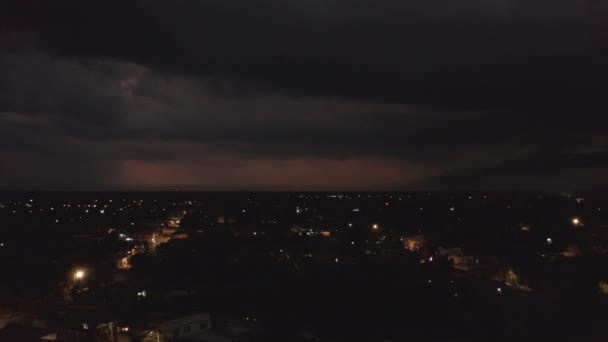 Повітряні панорамні кадри скромно освітлених вулиць у нічному місті. Великі хмари і шторм з блискавкою на відстані. Валладолід, Мексика. — стокове відео