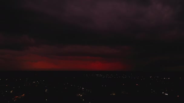 Лети над нічним містом. Червоні хмари і рідко спалахи блискавки. Шторм на відстані. Валладолід, Мексика. — стокове відео