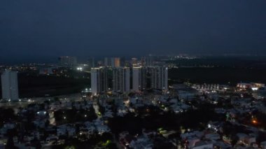 İleriye doğru yükselen sinekler gece kasabasının üzerinde. Lüks konut kompleksindeki modern uzun apartmanlar. Cancun, Meksika
