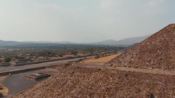 Vpřed letí za roh pyramidy. Odhalující panoramatický výhled na suchou krajinu a starobylou lokalitu.Starobylé místo s architektonicky významnými mezoamerickými pyramidami, Teotihuacan, Mexiko — Stock video