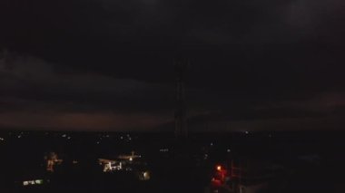 Banliyö, mobil operatör anten direği ve aydınlatılmış benzin istasyonunun panoramik yükselen görüntüleri. Gök gürültülü fırtına. Valladolid, Meksika