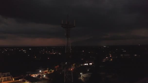 Fliegen Sie über Nacht Stadt. Bewegen Sie sich um einen Telekommunikationsmast. Dicke Wolken und Sturm in der Ferne. Valladolid, Mexiko — Stockvideo