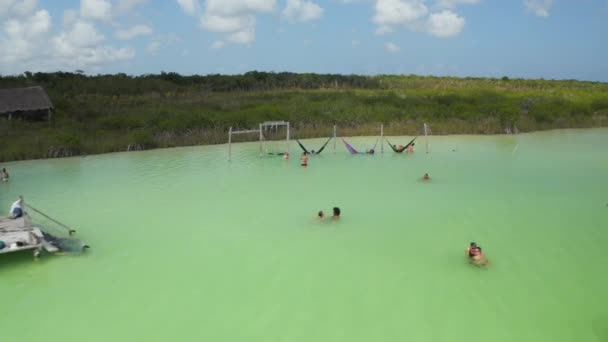 Snímek a pánev lidí, kteří si užívají horký den ve vodě. Pastelově zelená barva v přírodním jezeře v tropické destinaci. laguna Kaan Luum, Tulum, Yucatan, Mexiko — Stock video