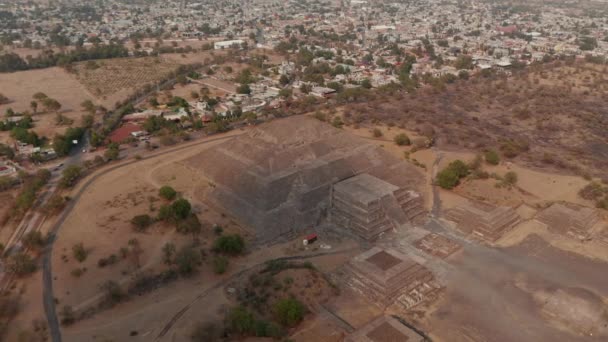 Dia- und Schwenk-Luftaufnahmen der Mondpyramide. Häuser in urbaner Nachbarschaft im Hintergrund. Antike Stätte mit architektonisch bedeutsamen mesoamerikanischen Pyramiden, Teotihuacan, Mexiko — Stockvideo
