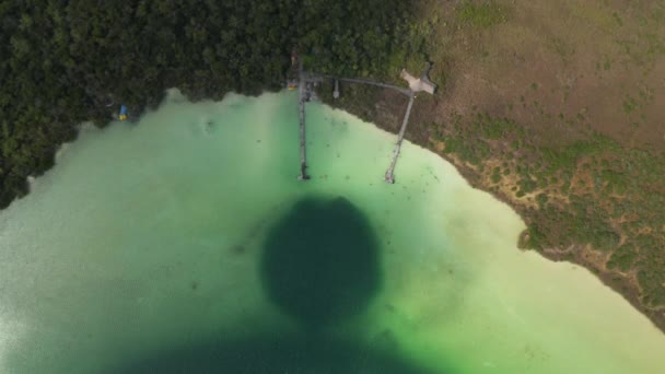 Vogelbeobachtung von oben nach unten Blick auf pastellgrünes Wasser im See und Menschen, die es sich an hölzernen Pfeilern gemütlich machen. Lagune von Kaan Luum, Tulum, Yucatan, Mexiko — Stockvideo