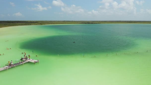 Backwards fly above amazing colourful lake in nature. People swimming and taking rest in sunny day. Kaan Luum lagoon, Tulum, Yucatan, Mexico — Stock Video
