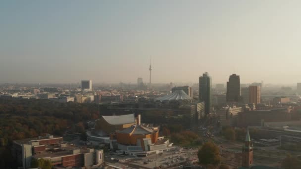 Vzdušný panoramatický výhled na město ozářený jasným ranním sluncem. Dopředu létají nad budovami Berlínské filharmonie. Televizní věž Fernsehturm v dálce. Berlín, Německo — Stock video