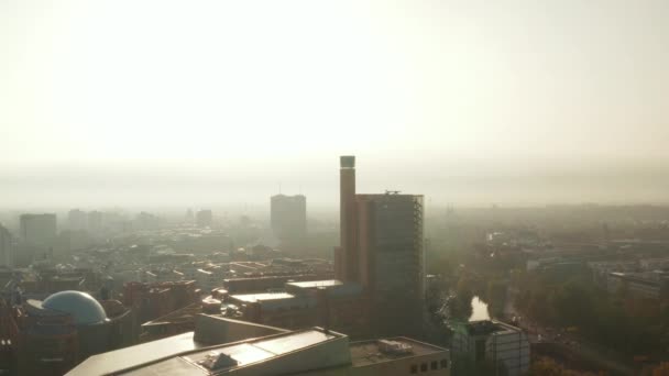 Vuela hacia un edificio alto en la ciudad en la orilla del río. Romántica mañana nebulosa vista contra el sol. Berlín, Alemania — Vídeo de stock