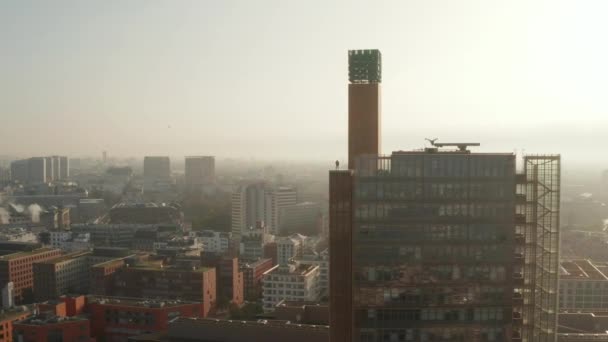 Dra tillbaka bilder av mannen som står på utsiktsterrassen på toppen av hög modern byggnad. Flygfoto mot morgonsolen. Berlin, Tyskland — Stockvideo