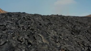 Soğutucu lav akışında biriken madde yığınlarının üzerindeki alçak uçuşlar. Patlayan volkanik madde katmanı. Fagradalsfall volkanı. İzlanda, 2021