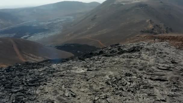 Soğutucu lav akıntısının üzerinde uç, çevreleyen arazinin üzerinde. Volkan patlamasından sonra volkanik manzara. Fagradalsfall volkanı. İzlanda, 2021 — Stok video