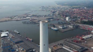 Danimarka, Esbjerg 'deki elektrik santralinin bacasının hava görüntüsü. Arka planda tuğla duvar ile şehrin ufuk çizgisinin çarpıcı drone görüntüsü