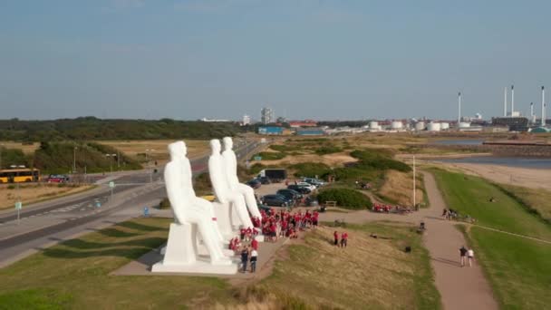 人の近くを飛行する空中ビューは、デンマークのEsbjerg海岸線の巨大な記念碑である海に会います。多数の観光客が訪れる巨大なランドマークを飛ぶドローンビュー — ストック動画