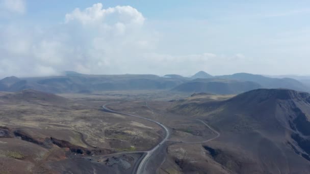 アイスランドの風景の美しい荒野の逆空中ビュー。山と崖の間のアイスランドのパノラマを走る環状道路のドローンビュー — ストック動画