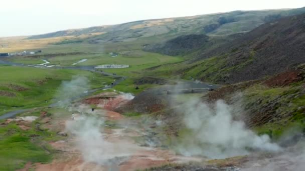 İzlanda 'da kraterleri buharlaştıran ve turist keşifleri yapan hava aracı manzaralı jeotermal alan. Fümerollerin gözleri ve sıcak su kraterleri. — Stok video