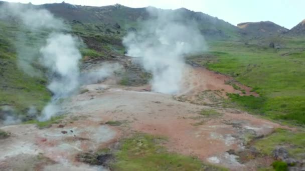 Бар'єрний вигляд паруючих геотермальних кратерів гарячої води в Ісландії. Повітряний вид на дивовижний геотермальний ландшафт з туристами, що досліджують пустелю. — стокове відео