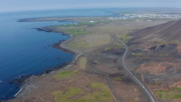 アイスランドの海岸線の景色のパノラマの風景。背景に街と黒砂の海のビーチと島の息をのむようなスカイラインのドローンビュー — ストック動画