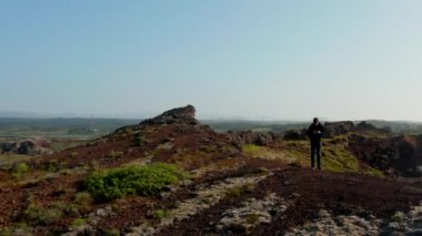 İzlanda 'da ayakta duran akıllı telefon kullanarak sırt çantalı gezginlerin hava görüntüsü. Genç adam turizm teknolojisinin insansız hava aracı görüntüsü panorama sörfü ağını görmezden gelmek bağımlısı