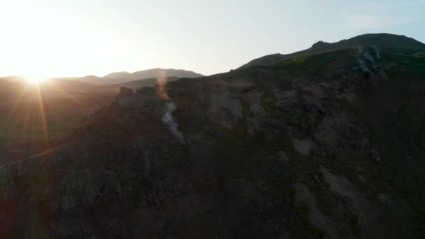 Orbita alrededor de formaciones rocosas con agua caliente humeante en Islandia. Vista aérea. Retroiluminación drone vista del paisaje geotérmico icelandés retroiluminación al atardecer — Vídeos de Stock