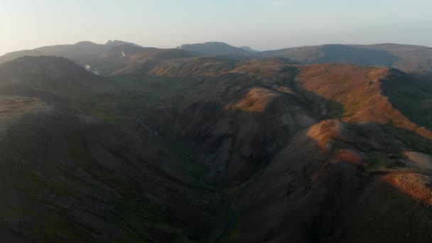 Drone vista deslizante sobre espectacular campo en Islandia. Aves vista aérea de las tierras altas musgosas con fumarolas humeantes en el fondo — Vídeos de Stock