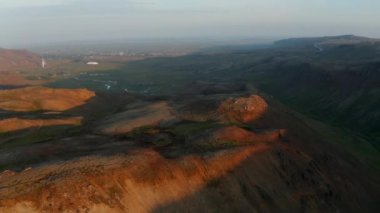 İnanılmaz hava manzaralı altın ışık dağları İzlanda 'da turuncu ryolit oluşumlarını yumuşatır. Dumanı tüten fümerolleri ve yosunlarla kaplı uçurumlarıyla insansız hava aracı manzarası