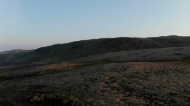 Göz kamaştırıcı kuşların gözü İzlanda dağlarının üzerinde. Doğada güzellik. İzlanda kırsalının panoramik manzarasının altın ışıklı günbatımı atmosferinin insansız hava aracı görüntüsü
