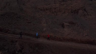 Kuşlar, İzlanda 'nın ıssız ve vahşi dağlık bölgelerinde turist yürüyüşü yapan üç kişiye bakıyor. Ay manzarası İzlanda 'nın dağlarını araştıran üç gezginin insansız hava aracı bakış açısı