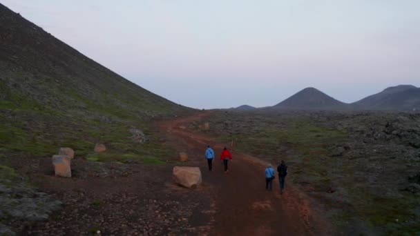 Aerial view orbit of group of sporty people walking pathway in isolated extreme panorama in Iceland. Drone view four people hikers mountaineering in icelandic isolated rocky desolate panorama — Stock Video