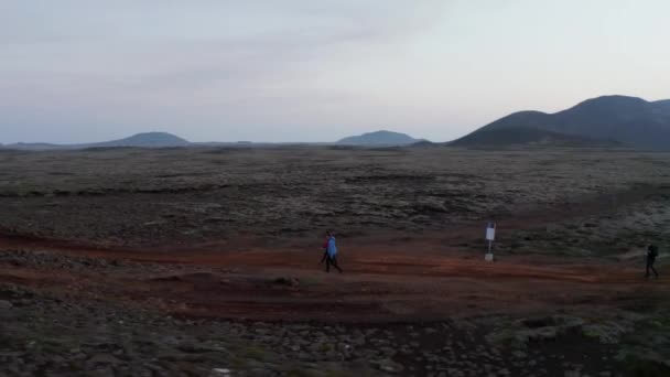 Drone omloppsbana synvinkel grupp av turist vandringsleder i isolerade steniga öknen på Island. Fåglar ögon resenär vandring utforska isbana — Stockvideo