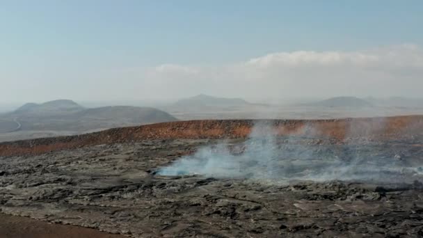 Volar sobre un gran agujero en la capa de lava de enfriamiento que emite humo. Paisaje volcánico tras erupción volcánica. Volcán Fagradalsfjall. Islandia, 2021 — Vídeo de stock