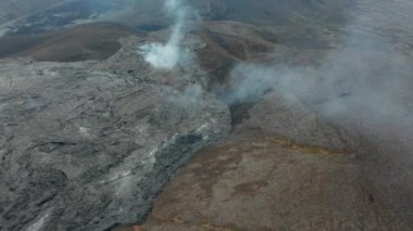 İleri doğru soğuk lav akımının üzerinde uçar ve beyaz duman bırakır. Yukarı kaldır ve panoramik manzara görüntüsünü göster. Fagradalsfall volkanı. İzlanda, 2021