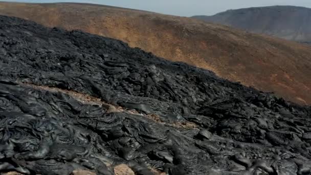 Slide και pan πλάνα από ευρύ ρεύμα λάβας, σκούρο ηφαιστειακό υλικό με τραχιά και τραχιά επιφάνεια. Το ηφαίστειο Fagradalsfjall. Ισλανδία, 2021 — Αρχείο Βίντεο
