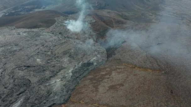 Adelante vuelan por encima de la corriente de lava enfriada liberando humo blanco. Inclinado hacia arriba revelan de vista panorámica del paisaje. Volcán Fagradalsfjall. Islandia, 2021 — Vídeos de Stock