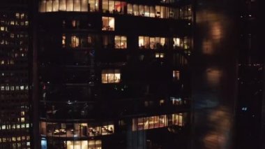 Geceleri modern gökdelenin alçalan görüntüsü. Gece geç saatlerde ofis pencereleri aydınlandı. Varşova, Polonya