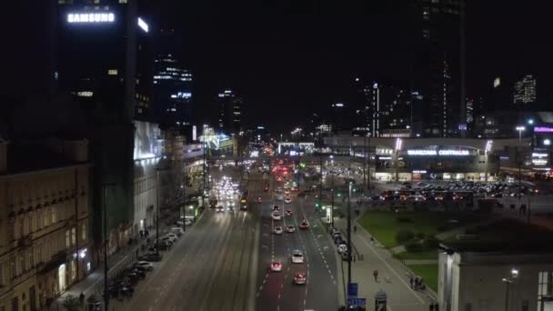 Images montantes de la circulation dense dans le centre-ville la nuit. Grande route à voies multiples menant entre les immeubles de grande hauteur et la gare. Varsovie, Pologne — Video