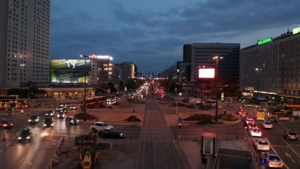 Circulation nocturne dans le centre-ville. Voitures conduisant à travers un grand rond-point traversé par des voies de tramway. Rues occupées au crépuscule. Varsovie, Pologne — Video