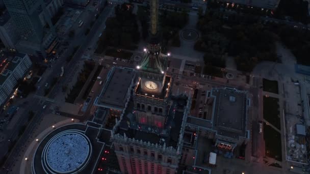 Hög ängel syn på spira med klocka på toppen av höghus byggnad. Kulturpalatset med omnejd på kvällen. Warszawa, Polen — Stockvideo